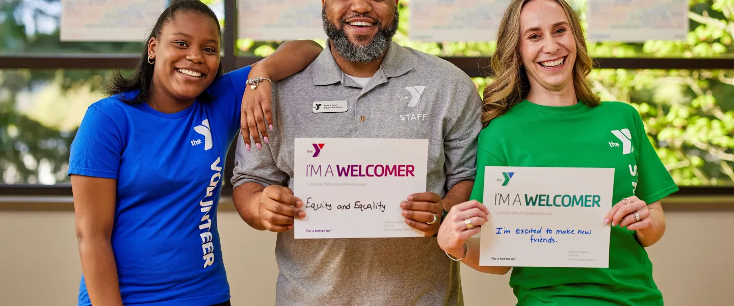 2 female and 1 male staff holding "I'm a welcomer" signs