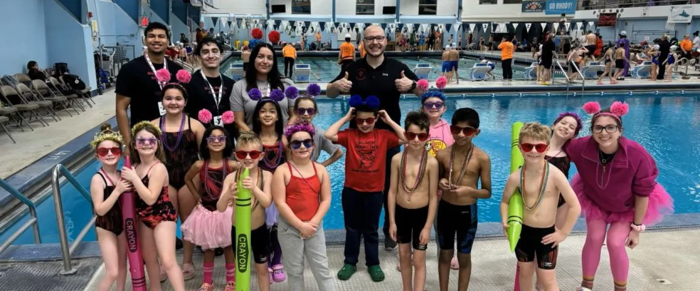 Swim Team posing with coaches at Swim Meet