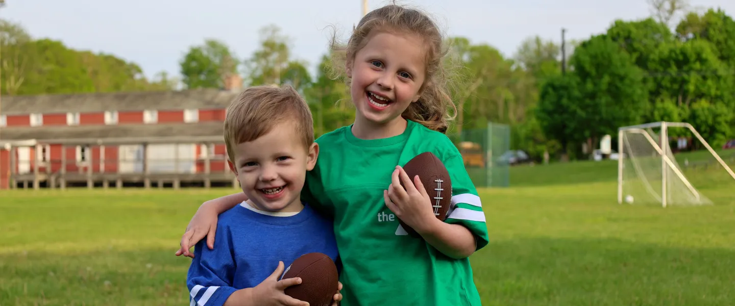 Boy and girl holding footballs