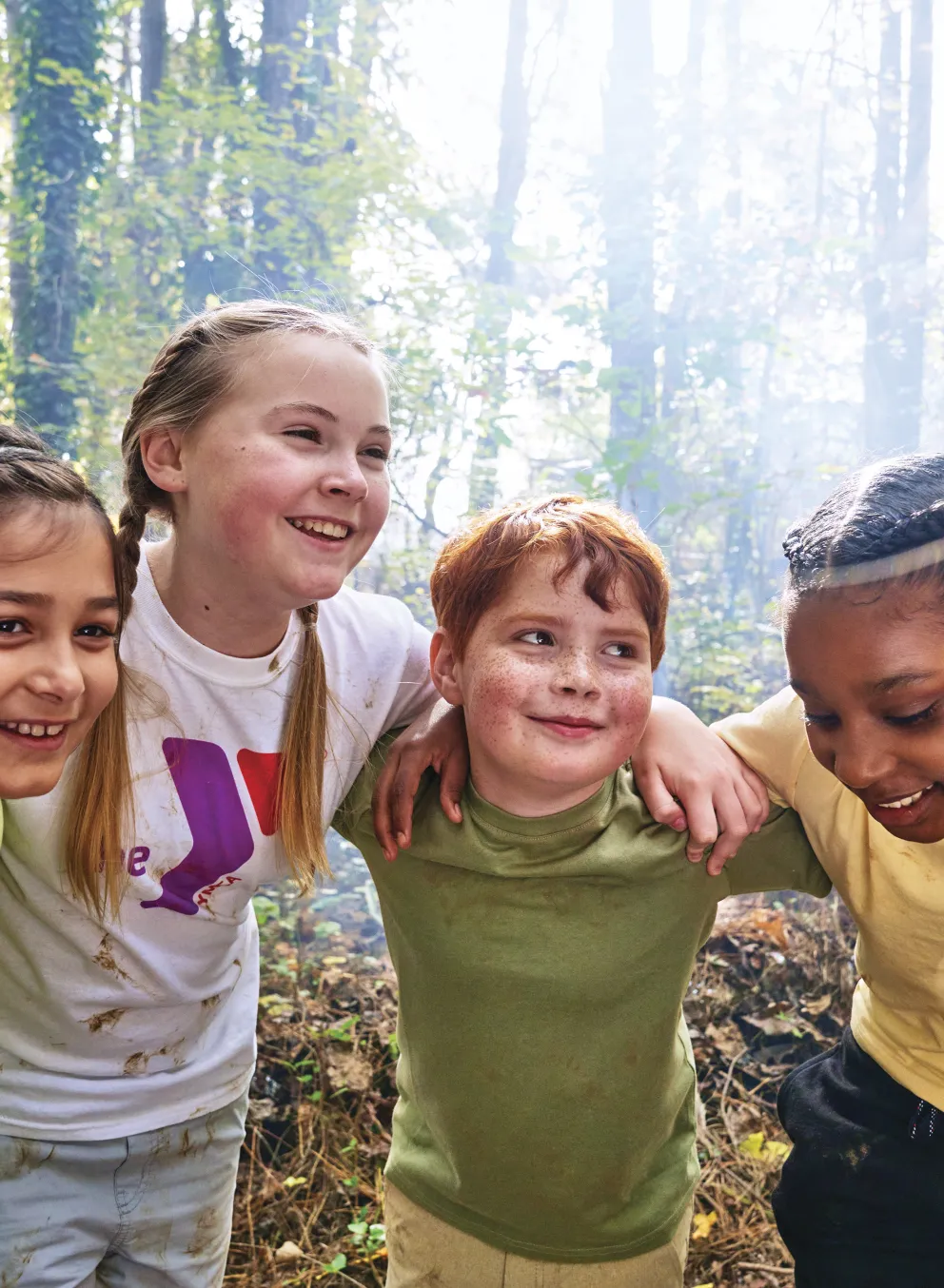 Group of kids smiling and huddling in the woods