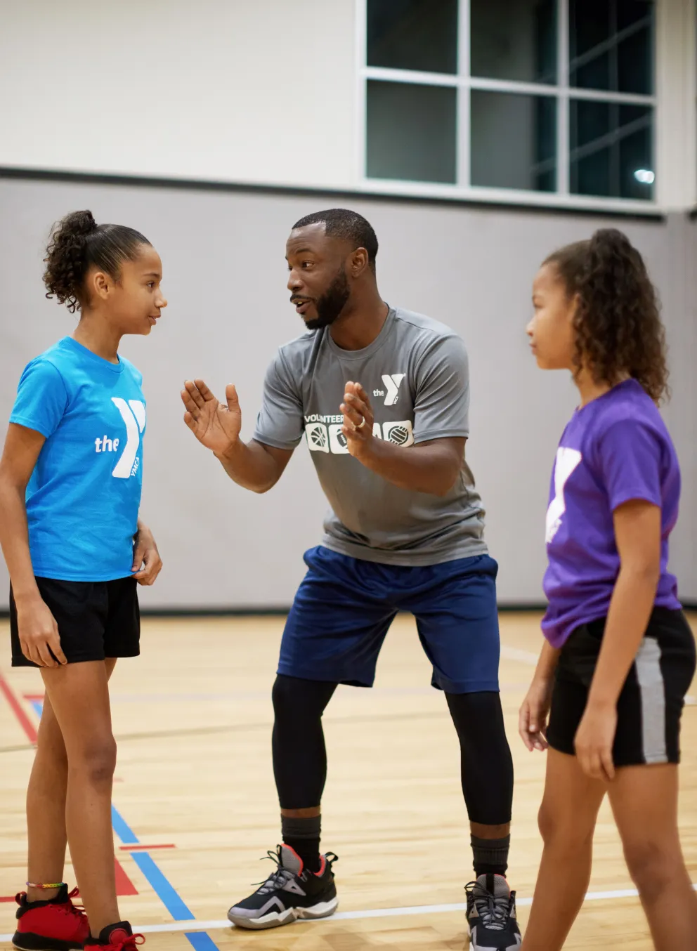 Male sports coach coaching to two female teenagers