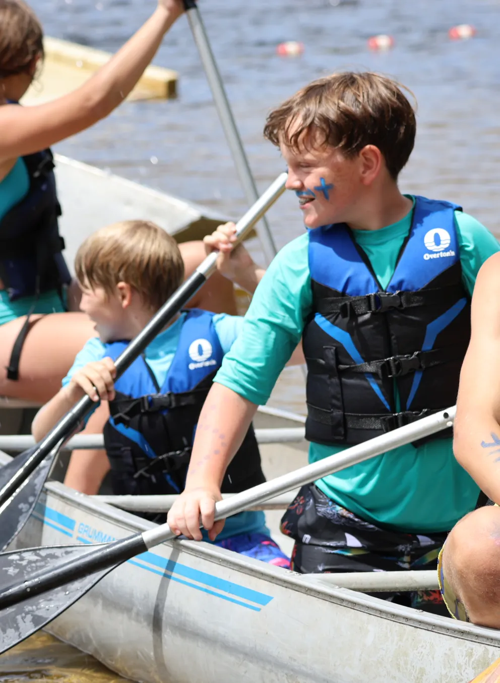 Boys Smiling in a canoe at summer camp on a lake