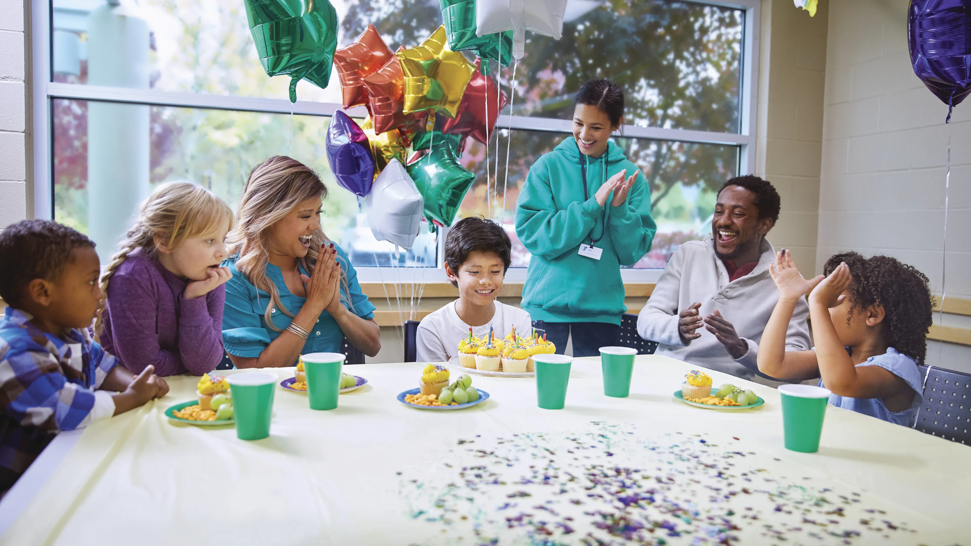 Kids sitting around a table celebrating a birthday