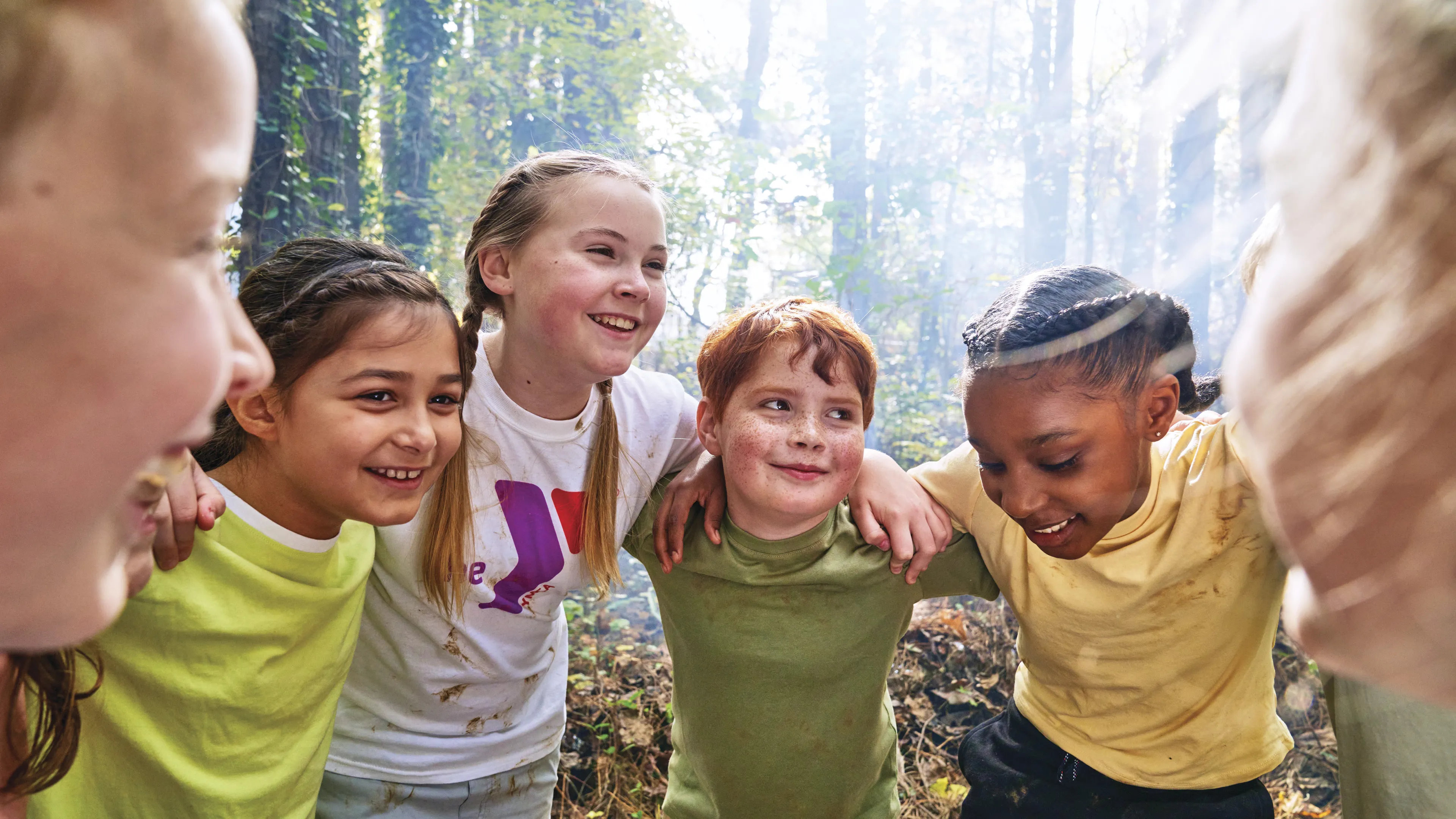 Group of kids smiling and huddling in the woods
