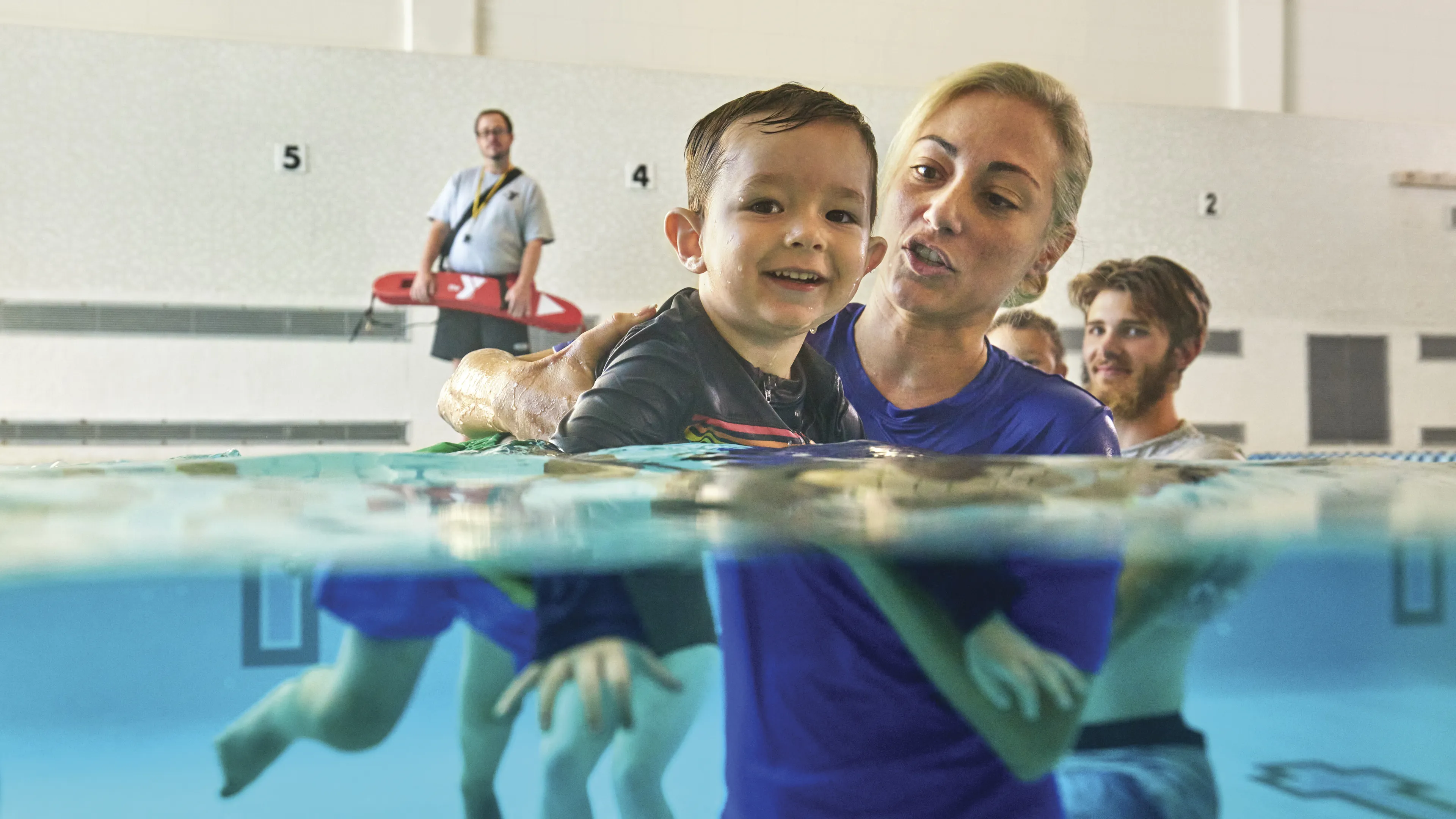 Female swim instructor teaching a young boy to siwm