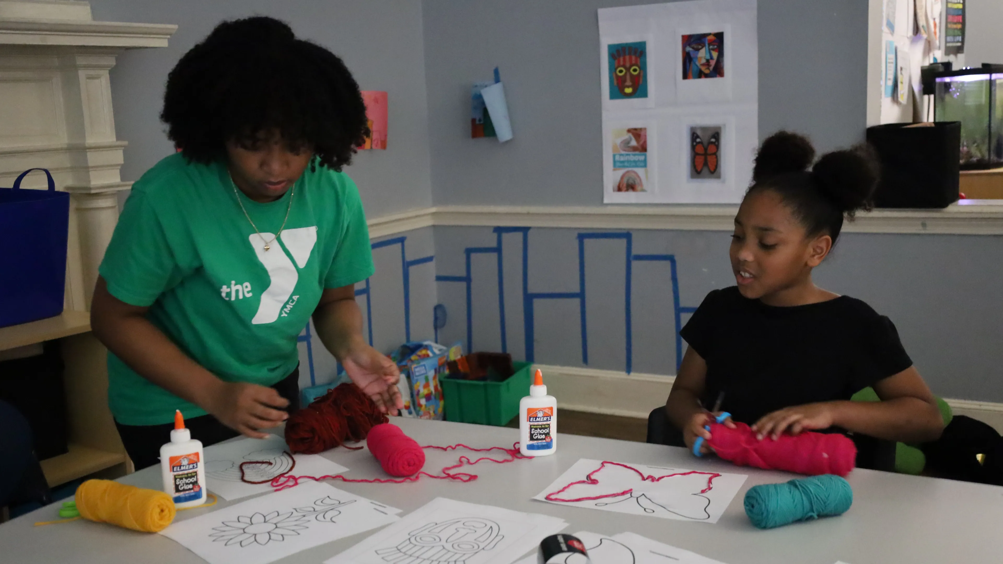 Female staff assisting a girl with her art project