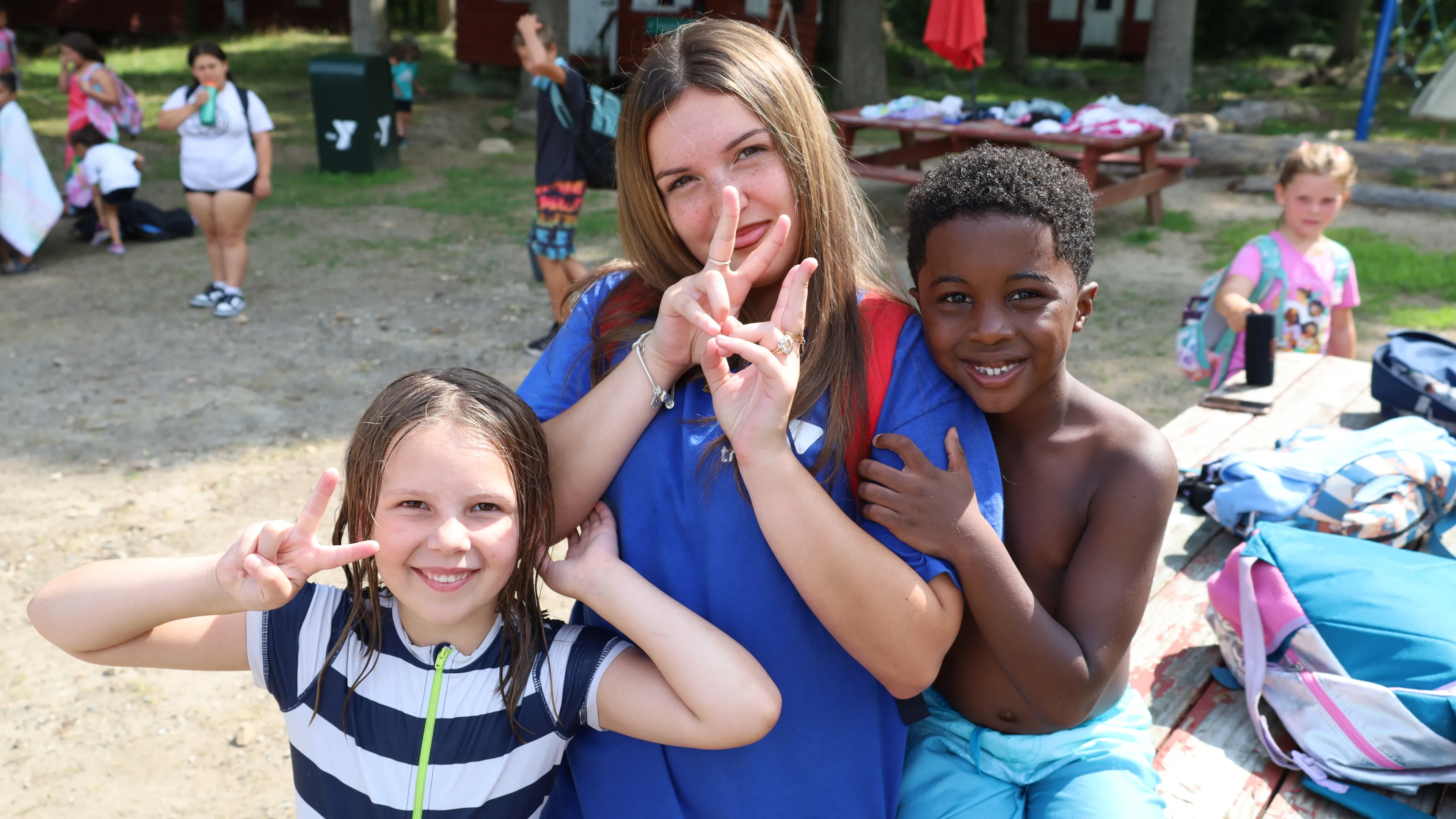 Camp Counselor smiling with campers kids on the beach at the lake