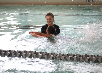 Female swim instructor teaching a girl how to swim with a kickboard