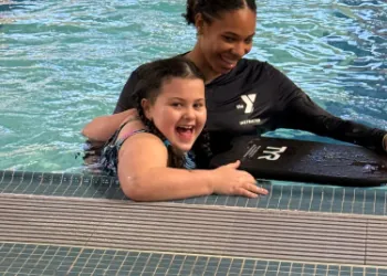 Kid in swim lessons being assisted by swim instructor