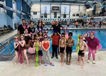 Swim Team posing with coaches at Swim Meet