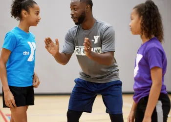 Male sports coach coaching to two female teenagers