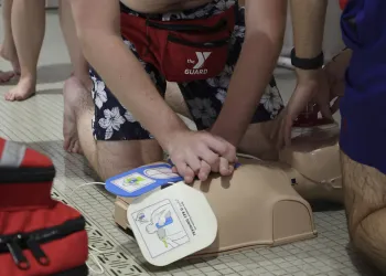 Male lifeguard practicing CPR on a dummy.
