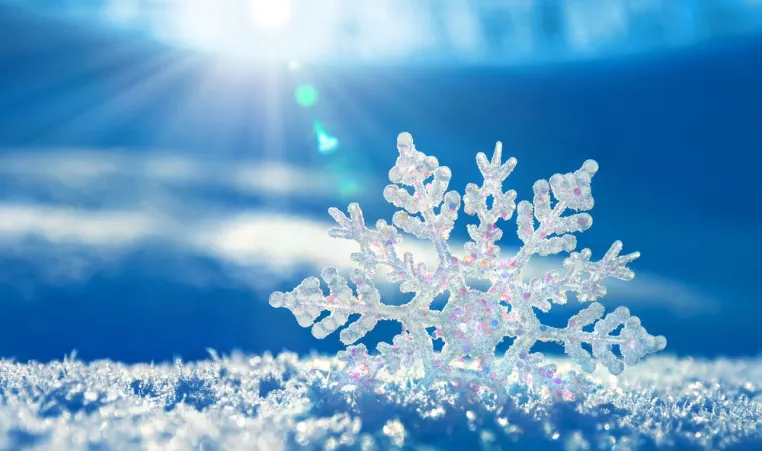 Snowflake with a blue background and the sun's rays trying to peek through.