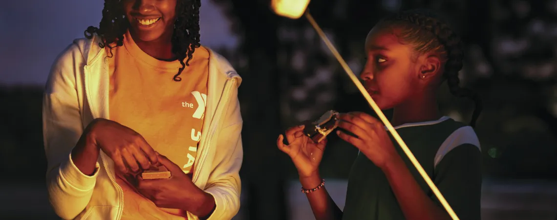 Camper and a staff having a smore