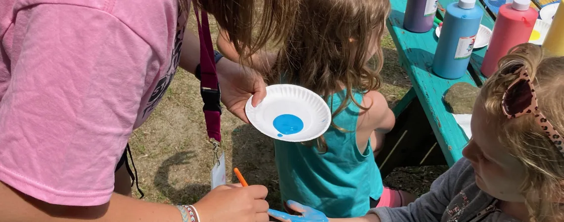 Counselor painting a child's hand blue for a craft