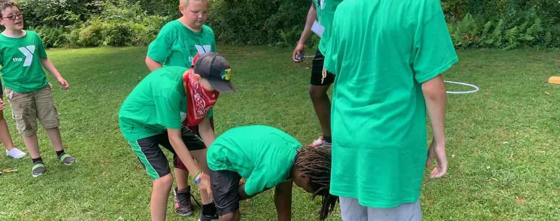 Boys participating in a relay race of passing an object underneath themselves