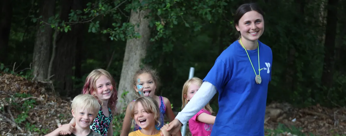 Female counselor standing with 5 campers