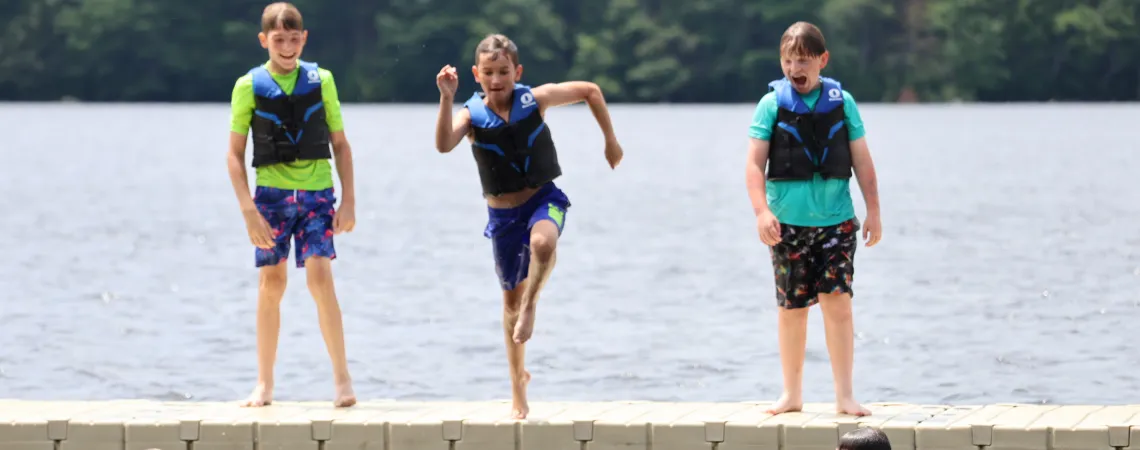 Summer Camp Kids Jumping Into Lake Smiling