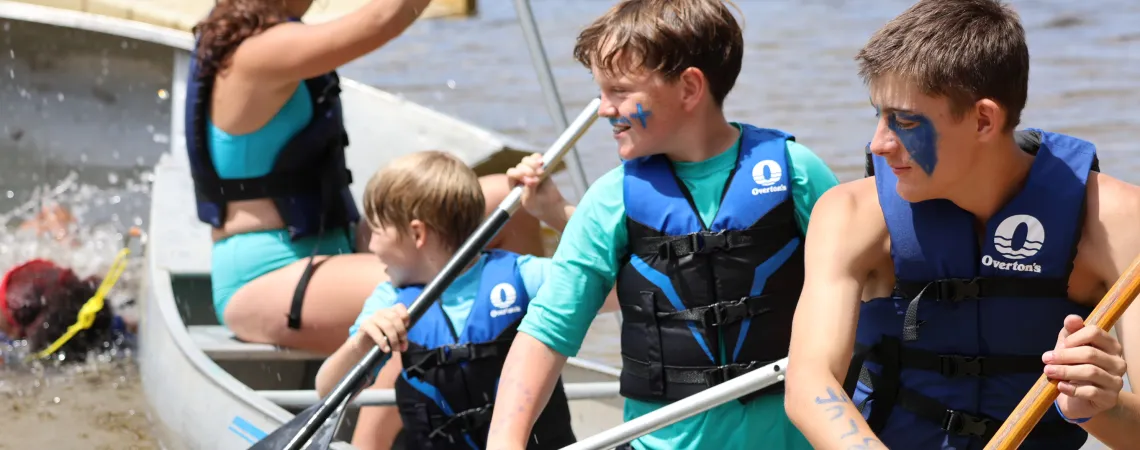 Boys Smiling in a canoe at summer camp on a lake